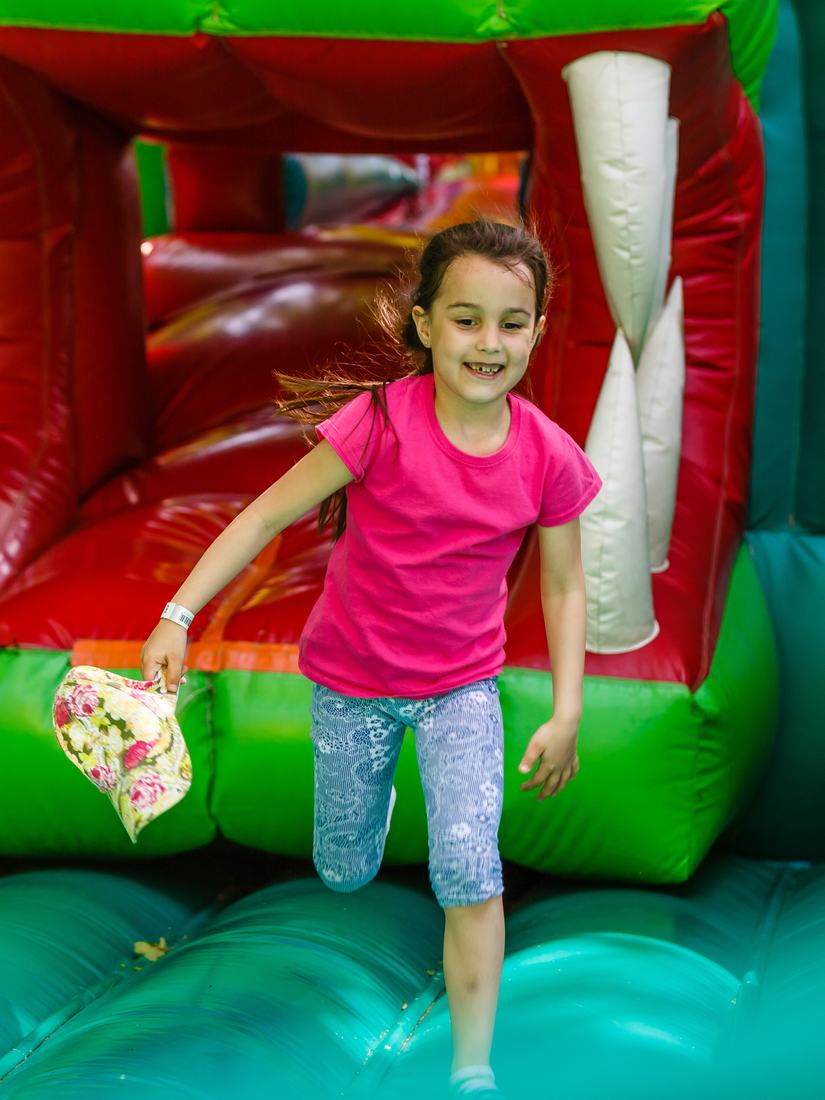 Smiling girl running out of a shark-mouth bounce house