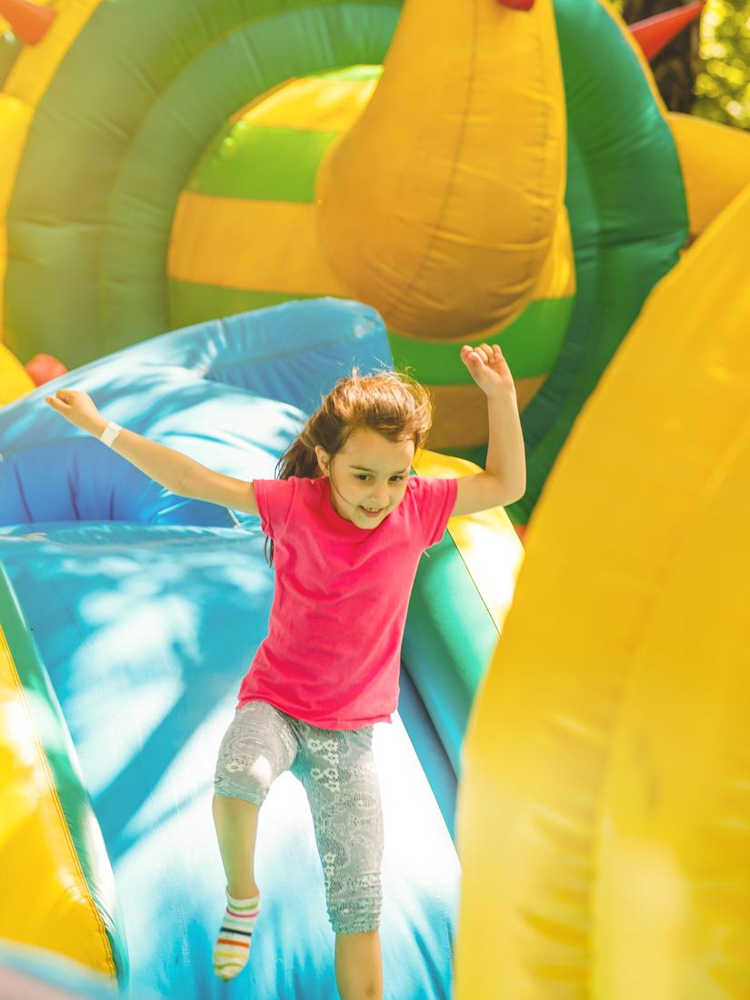 Girl jumping on a bright yellow inflatable slide